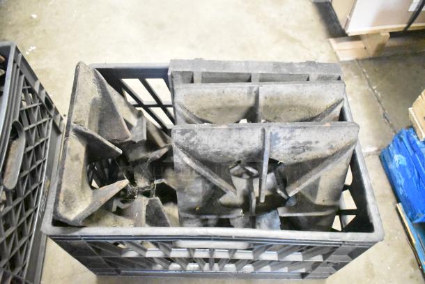 Nine metal range grates in used condition, stacked in a crate. Showing signs of wear, suitable for replacement or parts.