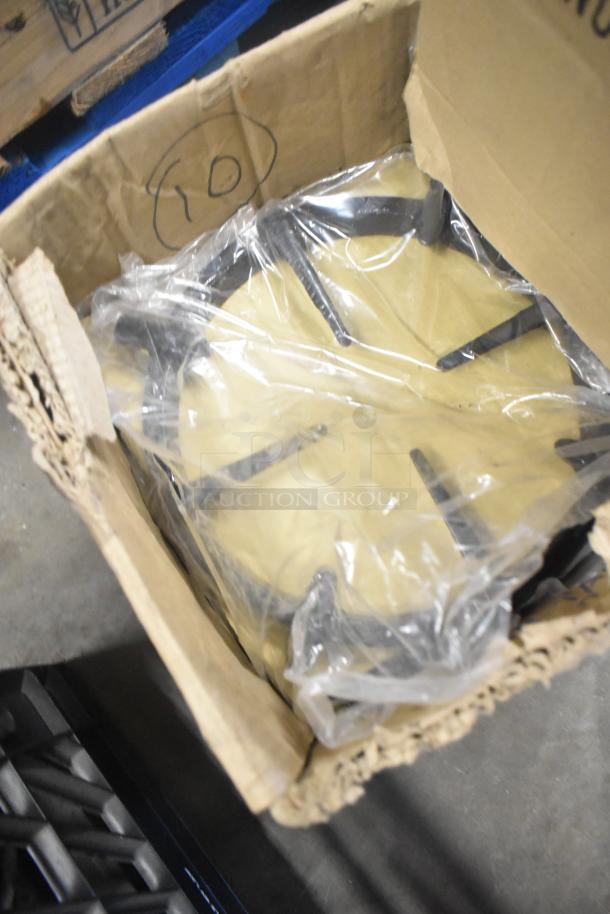 Nine metal range grates in cardboard box, lightly used, some in plastic wrap, labeled "10" on box interior.