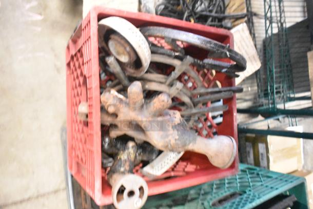 Alt text: Red crate filled with miscellaneous items including range burners, grates, and wires. Items appear used and rusty.