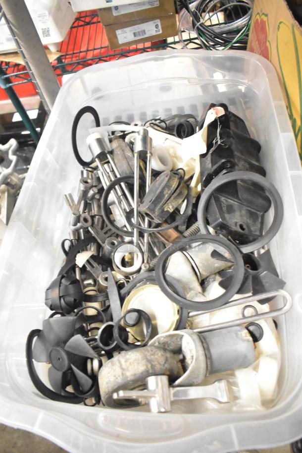 Bin of assorted machine parts, including Taylor ice cream machine and beverage adapters, various metal and rubber components.