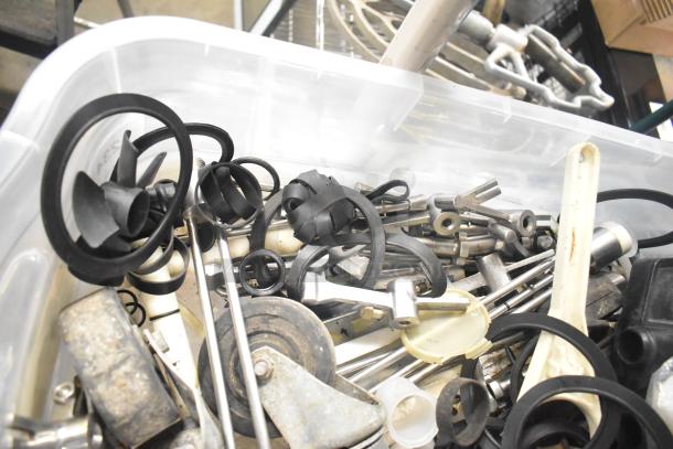 Assorted lot of machine parts including Taylor ice cream machine parts and carbonated beverage machine adapters in a plastic bin.