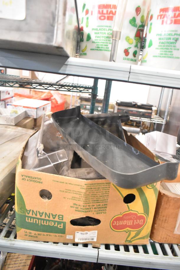 Box containing Taylor ice cream machine parts and carbonated beverage machine adapters on shelf. Items in used condition.