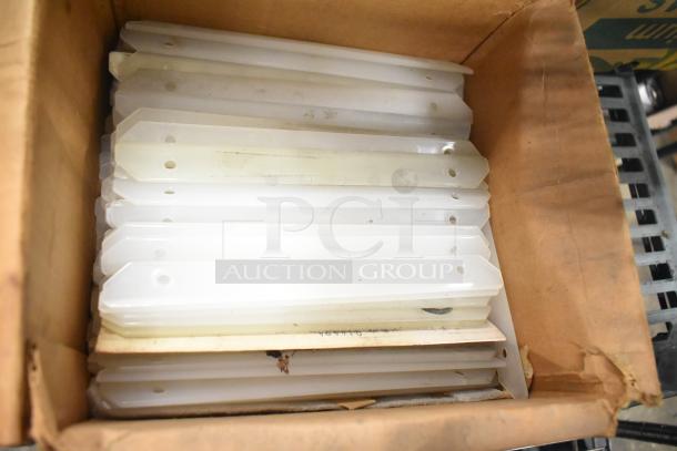 Box of Taylor ice cream machine parts, including white plastic components with mounting holes, showing moderate wear.