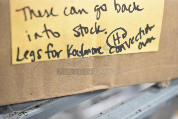 Cardboard box with a handwritten note: "These can go back into stock. Legs for Kenmore convection oven."