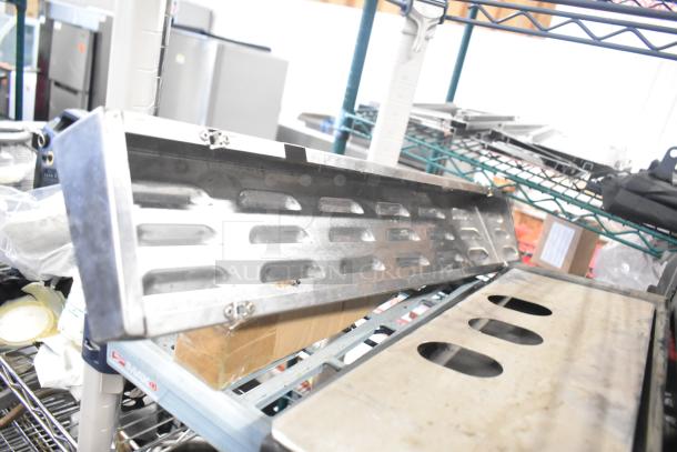 Tier lot of various items including Turbochef kickplate and drip trays. Items are metallic and in used condition.