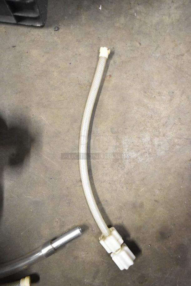 Assorted equipment lot featuring a flexible hose with connectors, shown on a concrete floor. Suitable for various machine parts.