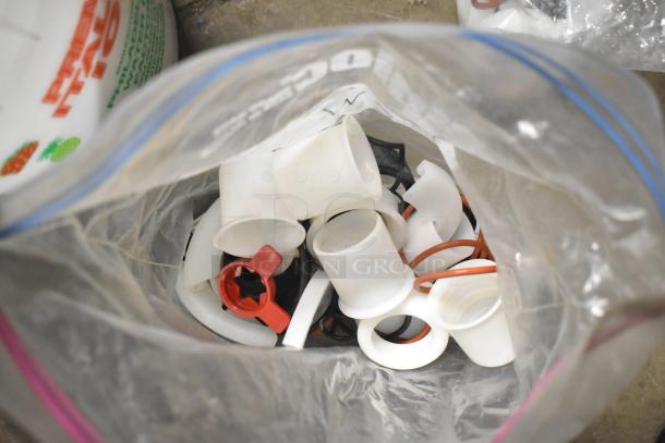 Bag of assorted plastic parts including rings and caps, used condition. Ideal for equipment maintenance and repairs.
