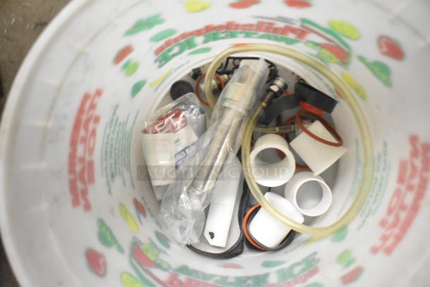 Tiered lot of miscellaneous items in a bucket, including a Turbochef kickplate, Taylor ice cream machine drip tray, and beverage machine parts.