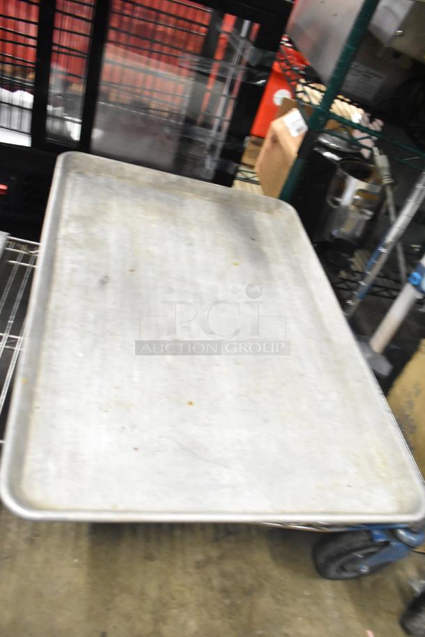 Metal baking pan on wheeled cart, visible wear. Includes 12 various items like stainless steel drop-in bins. Auction lot.