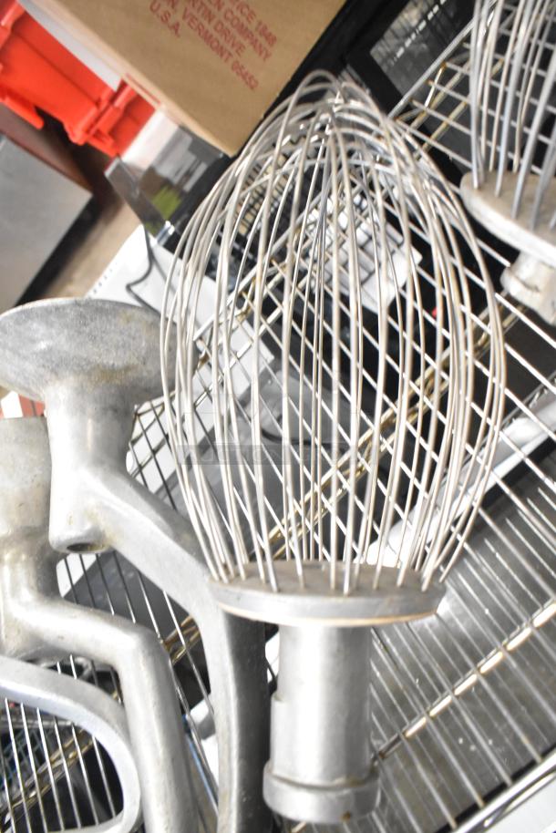 15 Hobart mixer attachments, including dough hooks, paddle whips, and whisks, shown in good condition.