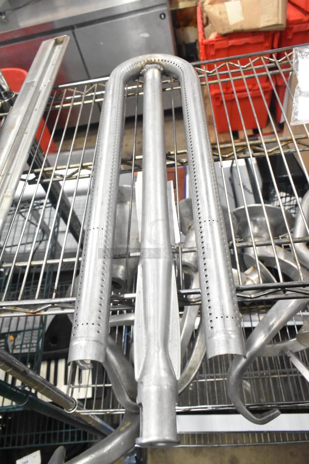 Metal burner tube on a wire rack, used condition, industrial kitchen component, visible perforations for gas flow.