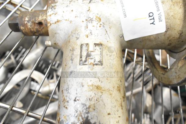 Rustic meat grinder attachment with visible "H" marking, aged metal surface, in used condition with attached identification tag.