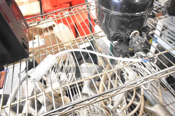 Cubigel NUT70NR Compressor, black finish, 115-127V, 1 phase, mounted on wire shelf. Visible connector and wiring.