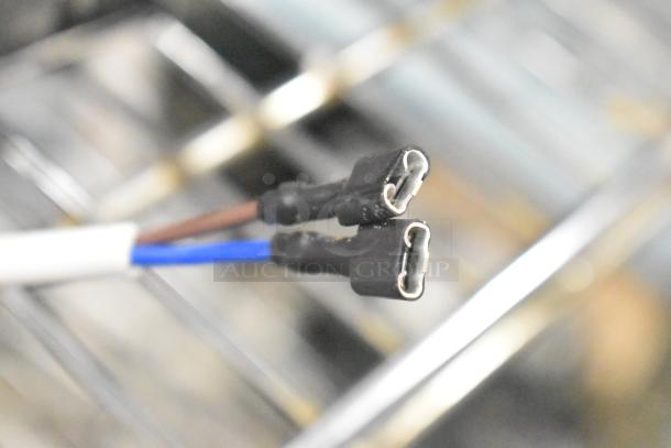 Blurred close-up of two electrical wire connectors. No visible markings or labels. Part of Cubigel NUT70NR Compressor.