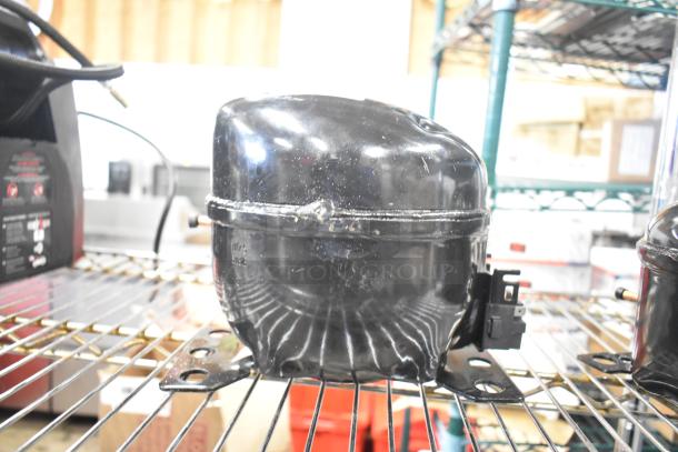 Cubigel NUT70NR Compressor, 115-127 Volts, 1 Phase, black, used condition, mounted on metal shelf.