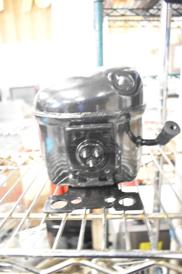 LG TS24LACG Compressor, 115V, 1 Phase, in good condition on metal rack; features mounting base and connection ports.