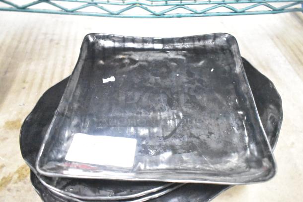 Six assorted black baking pans and skillets stacked, showing wear. Auction tag indicates "6 times your bid" offer.