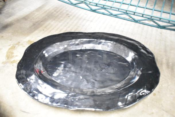 Black metal baking pan, oval shape, reflective surface, minor scuffs, part of a lot including baking pans and skillets.