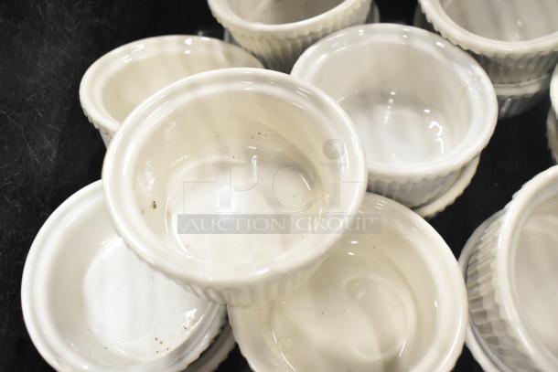 White ceramic ramekins with ribbed sides, part of a tiered auction lot. Slightly soiled, used condition.