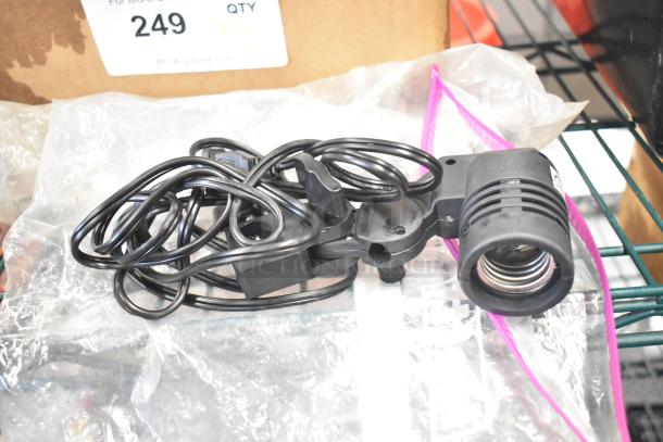 Assorted auction lot with black light fixture, coiled black cables, atop plastic wrap on metal shelving, labeled "249."