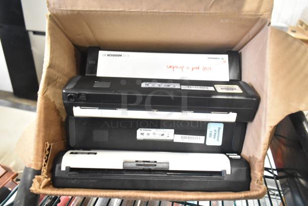 Cardboard box containing several electronic devices with visible labels, including Visioneer and Polaroid brands.