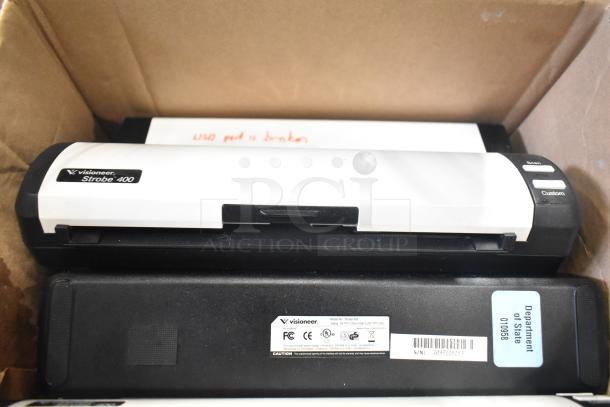 Box containing Visioneer Strobe 400 scanner with visible labels and markings, part of a mixed auction lot.