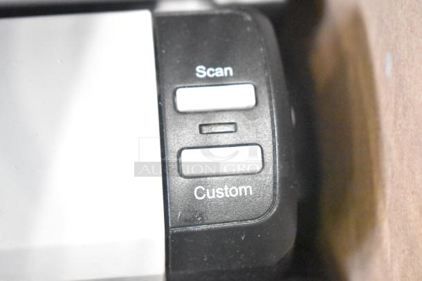 Close-up of a device with white "Scan" and "Custom" buttons on a black panel.