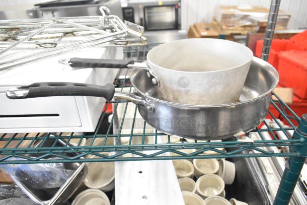 Metal cash drawer, two sauce pans, and chrome brackets on a kitchen shelf, used condition.