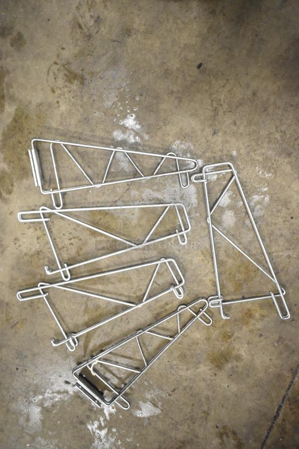 Chrome finish brackets on concrete floor, part of an auction item set including cash drawer and sauce pans. Good condition.