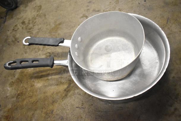 Two metal saucepans with black handles, showing signs of wear, part of an auction lot with cash drawer and chrome brackets.