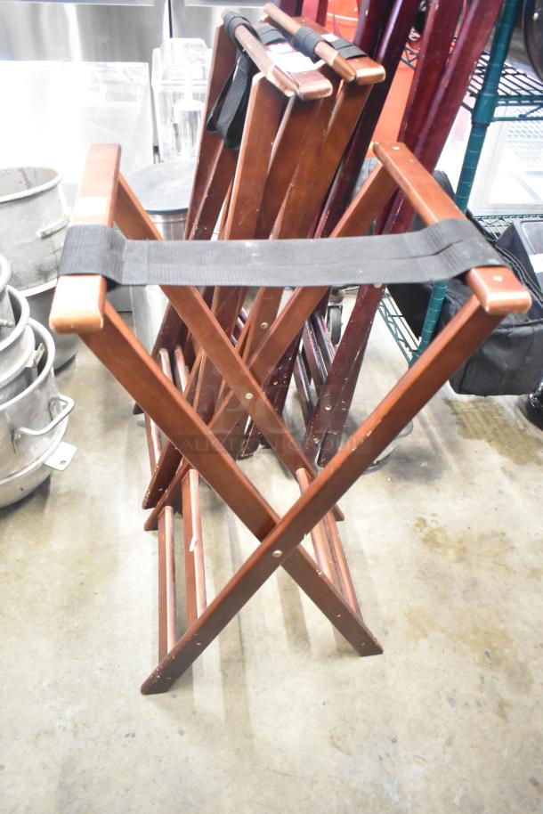 Set of 5 wooden serving tray stands in good condition, with black straps for stability. Auction includes all five stands.