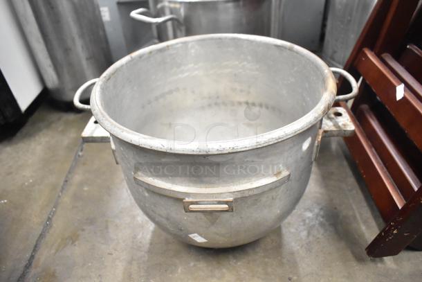 Large industrial metal mixing bowl with handles, used condition, noticeable wear. Ideal for commercial kitchens.