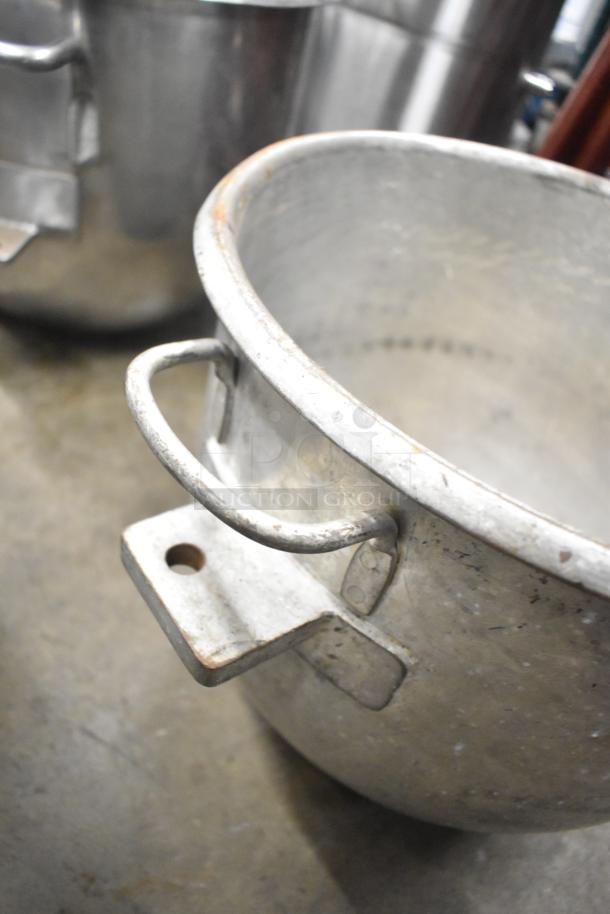 5 various metal mixing bowls with handles, visible wear, industrial design, ideal for heavy-duty kitchen use.