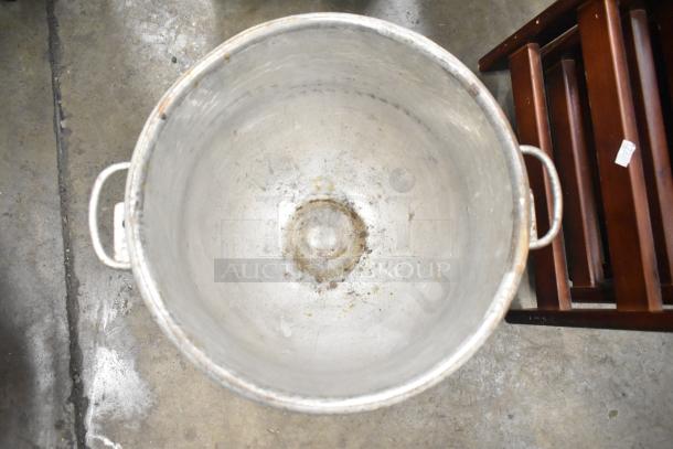 Large metal mixing bowl with dual handles, showing wear and patina, indicating vintage and utility.