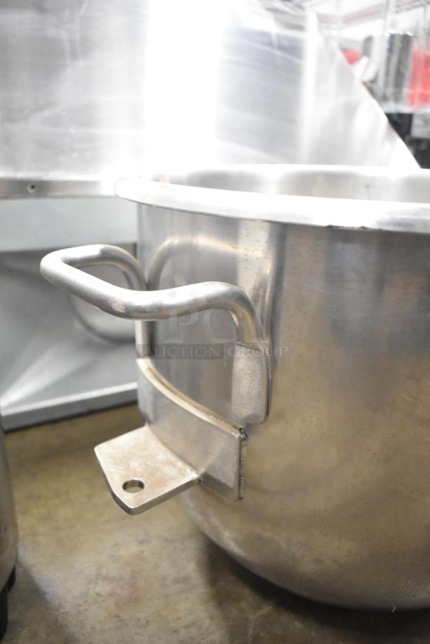 Five metal mixing bowls with sturdy handles, commercial-grade, showing some wear. Ideal for kitchen use, auction item.