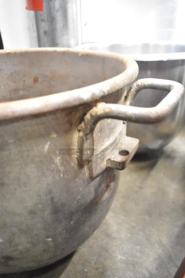 Five metal mixing bowls with handles, showing signs of wear and age. Various sizes, suitable for heavy-duty kitchen use.