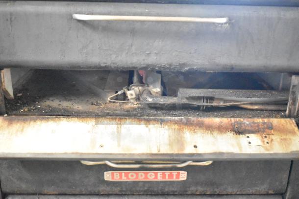 Blodgett commercial gas pizza oven with two decks, visible wear and grime, sturdy handles, Blodgett logo on front.