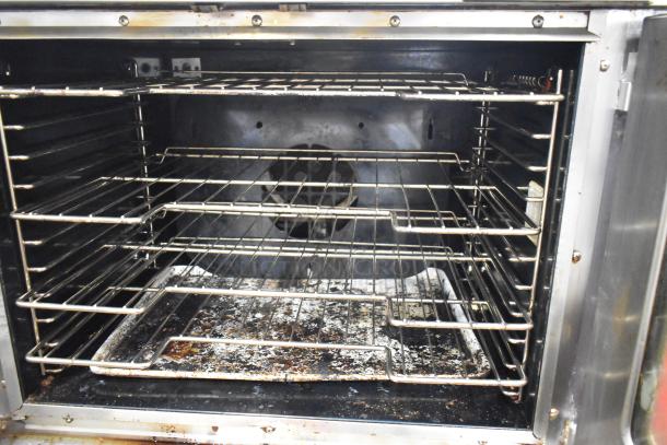 Vulcan commercial convection oven with view-through doors and thermostatic controls, showing interior racks and wear marks.