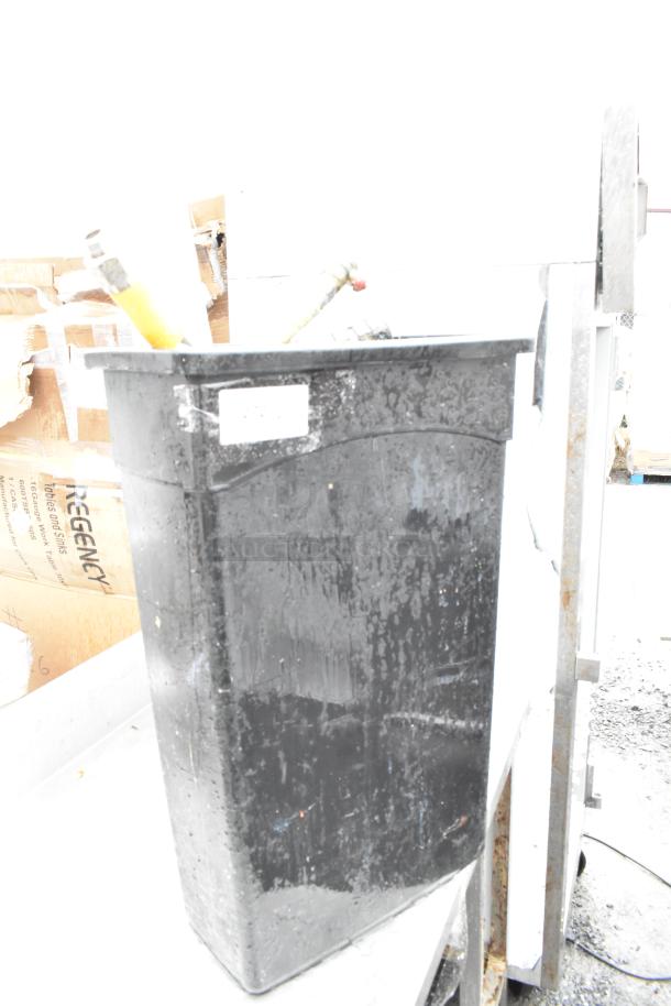 Black Poly Slim Jim trash can, used, with visible label; contains gas hoses, some wear evident.