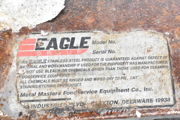 Eagle Group stainless steel table tag, shows care instructions and guarantees against defects. Appears aged with visible wear.