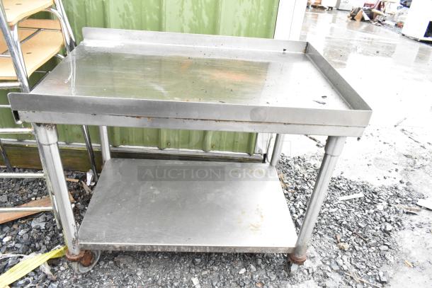 Stainless steel 2-tier cart with commercial casters, used condition, visible wear and rust on wheels, suitable for industrial use.