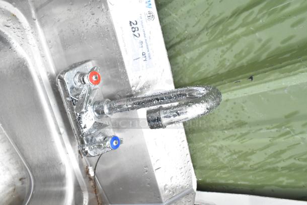 Commercial single bay wall mount sink with faucet, hot/cold handles, and side splash guards, in good condition.