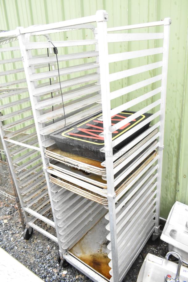 Commercial pan transport rack with casters, filled with baking pans. Used condition, sturdy metal frame, ideal for bakery use.