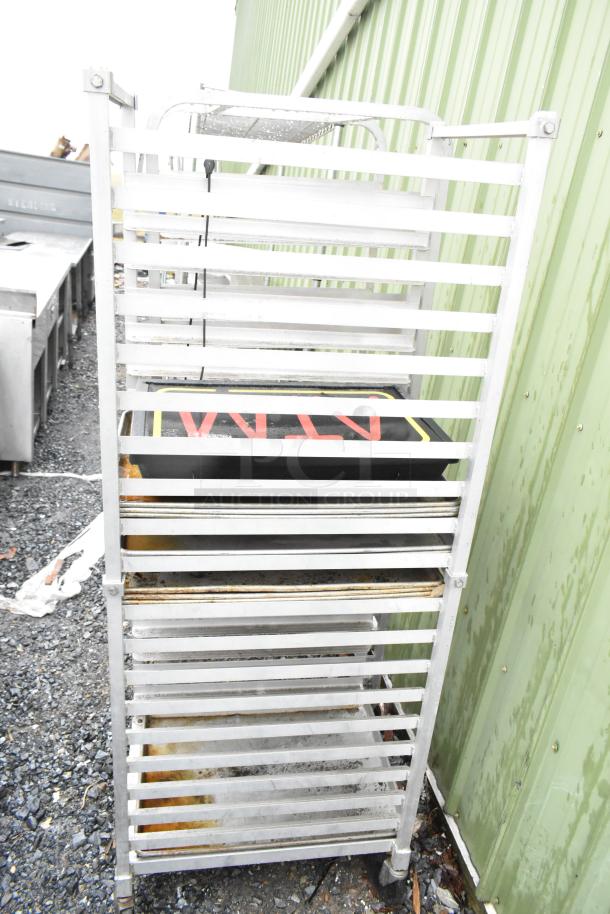 Commercial pan transport rack with casters, includes multiple baking pans. Used condition, visible rusting on metal frame.