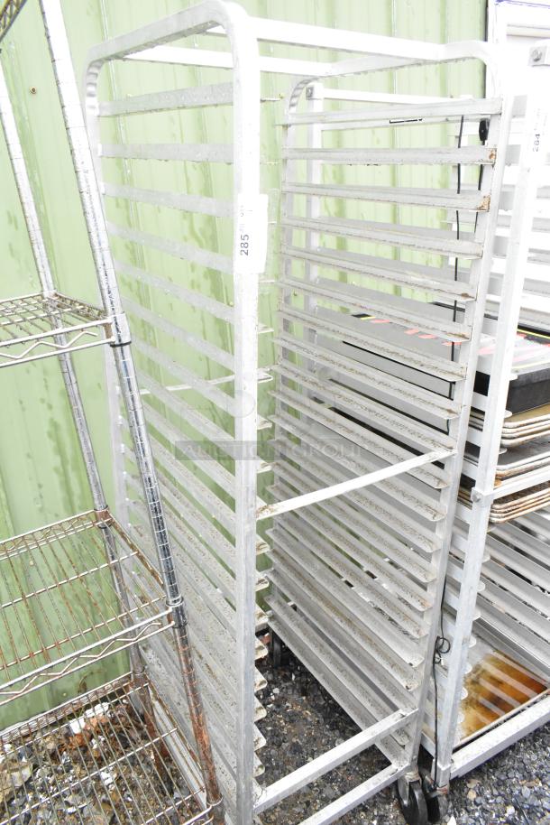Commercial pan transport rack with multiple shelves, on sturdy casters. Visible wear. Tagged with label "285."