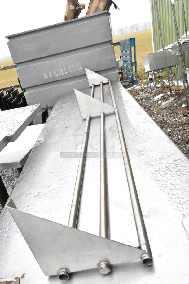 Metal tray slide with sturdy rods and angled brackets, in good condition, on a wet metal surface.