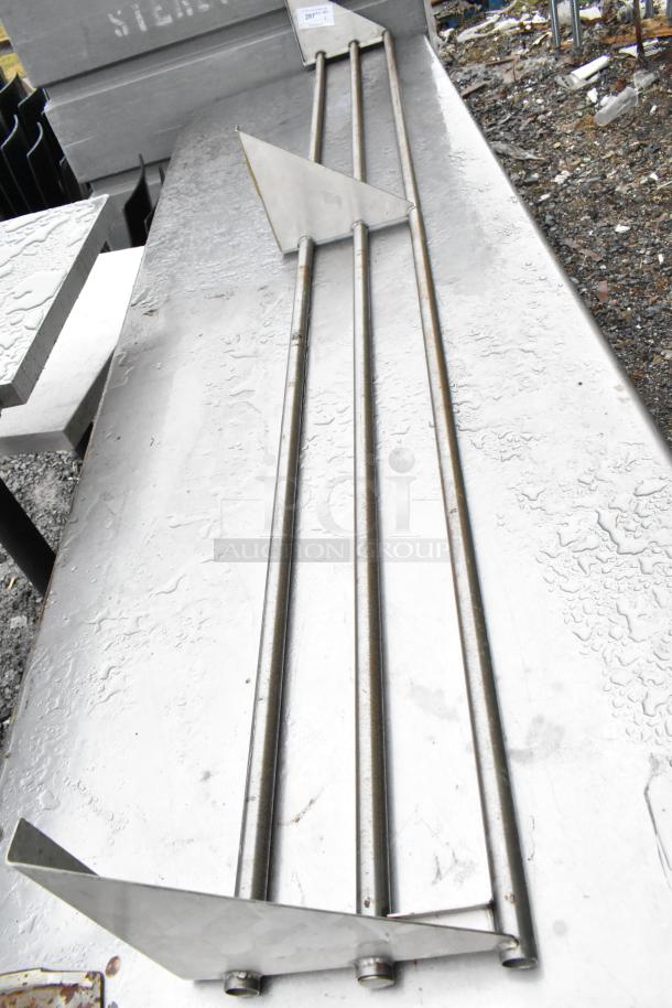 Stainless steel metal tray slide with three rods, triangular supports, and visible wear. Appears functional.