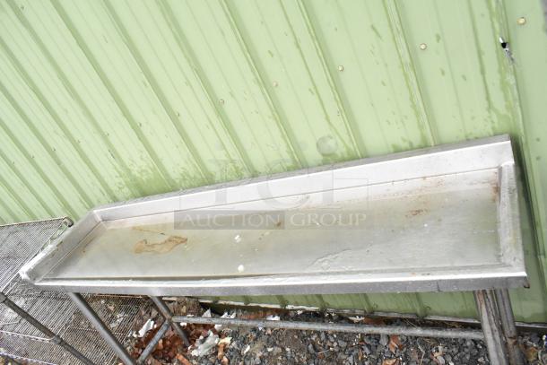 Stainless steel table, rectangular, with a raised edge, signs of rust and wear. Suitable for industrial use.