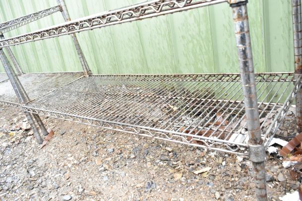 Chrome finish 3-tier wire shelving unit in need of dismantling. Outdoor condition with visible wear and some rust.
