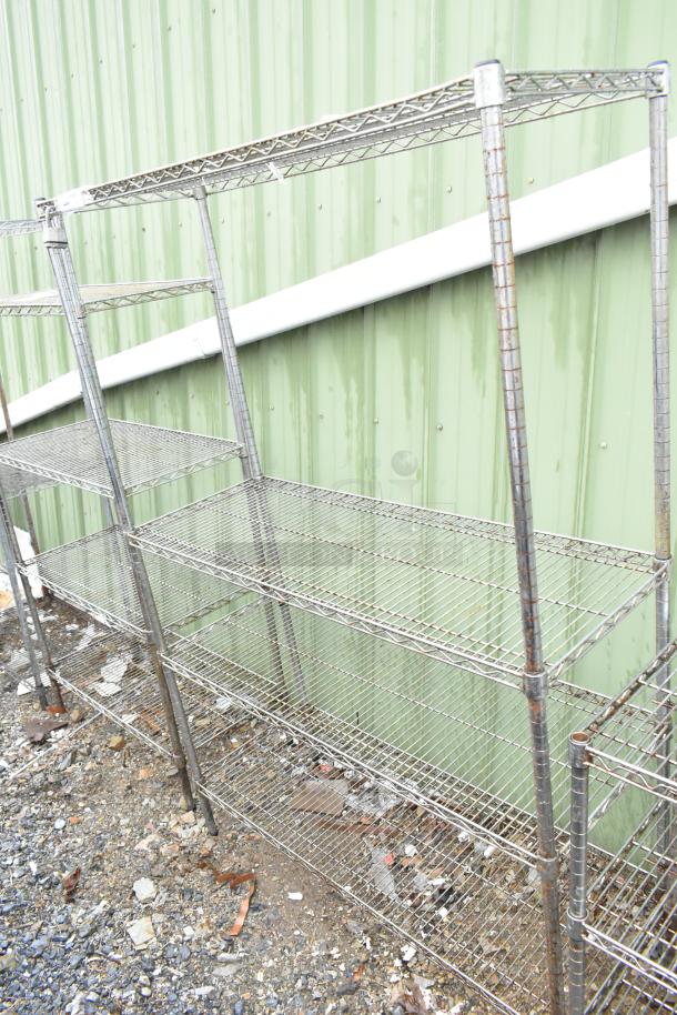 Chrome finish 4-tier wire shelving unit, evident signs of wear, buyer must dismantle, located outdoors on gravel.